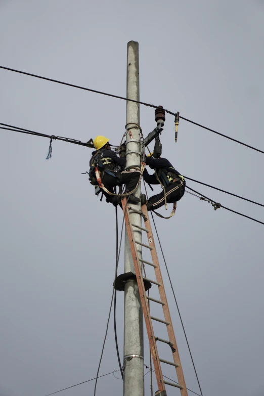a man who is on a ladder on some electrical wires