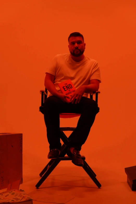 a man sitting in a chair, with a red background