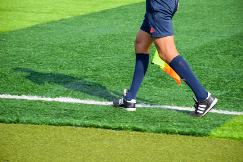 a person walking on the field with a soccer ball in their hand