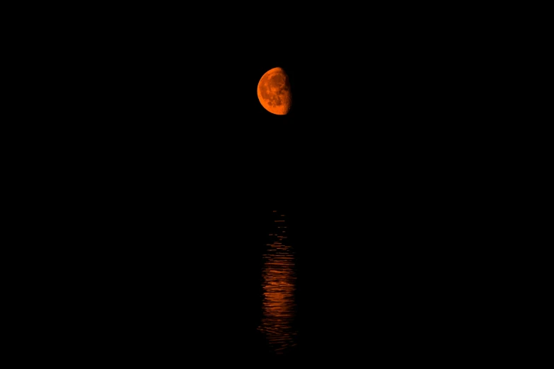 a full moon rising over the water on black sky