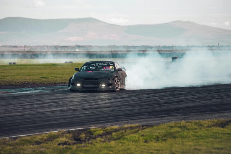 a black car with smoke in the road