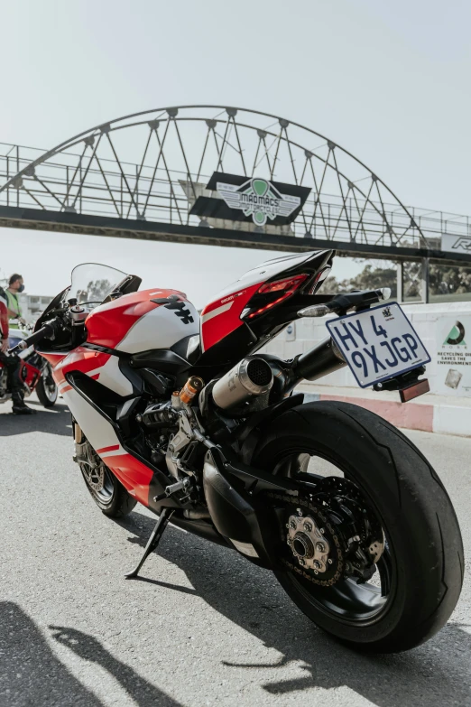 a red motorcycle parked in a parking lot next to a bridge