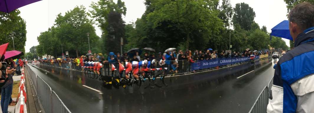 spectators stand in the rain while holding umbrellas