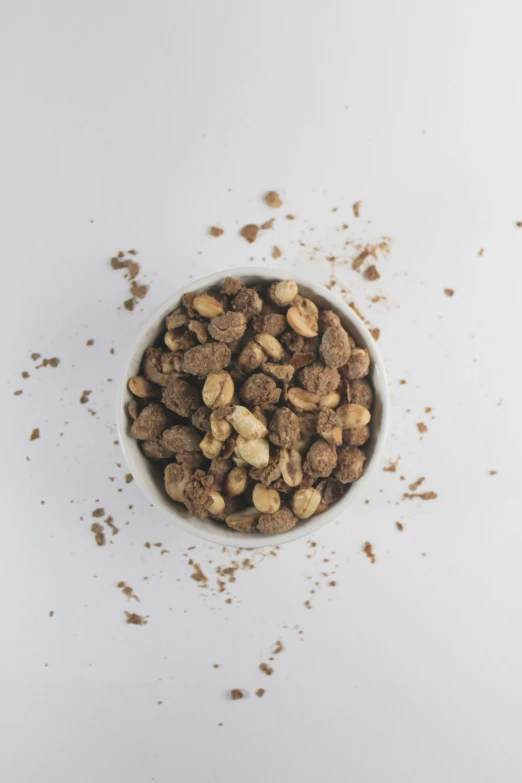 a bowl full of nuts on a white surface