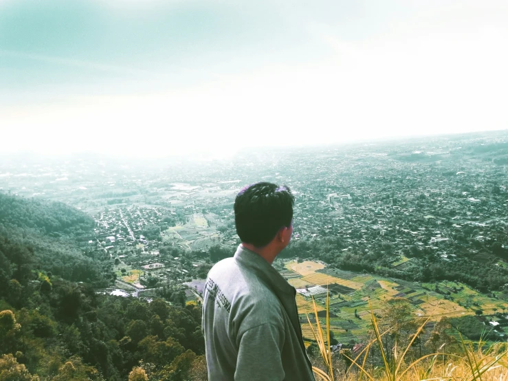 a man looking out at the city and countryside from a lookout