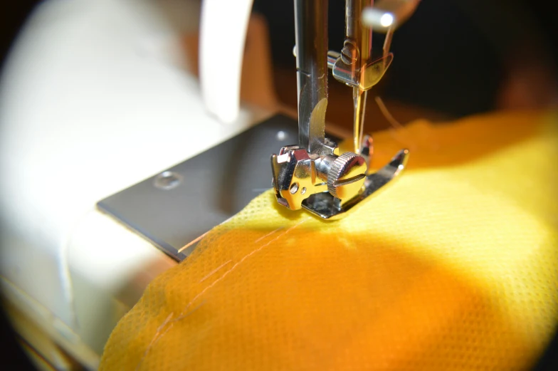 a sewing machine  through the needle of an orange cloth