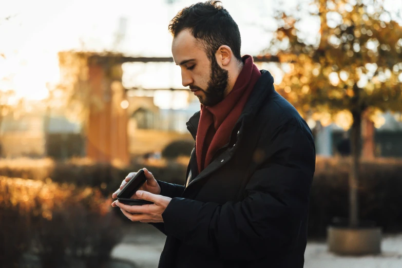 the man is standing in front of the bridge using his phone