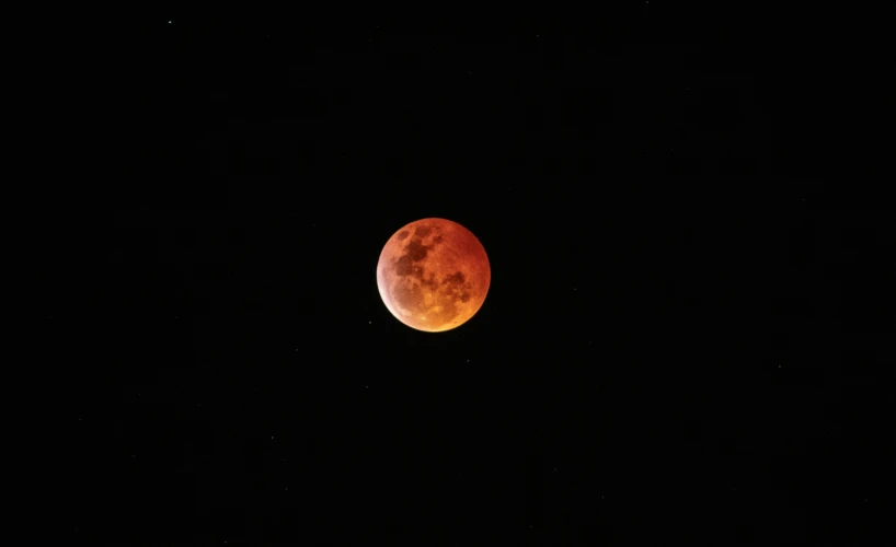 an orange moon with stars in the sky