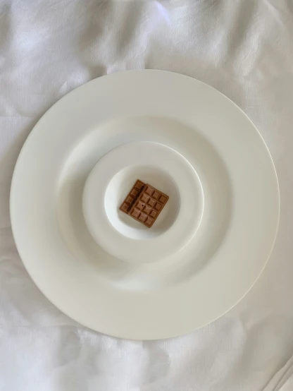 white and brown plate with square food on the bottom