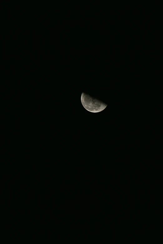 the moon seen from a distance in the dark sky