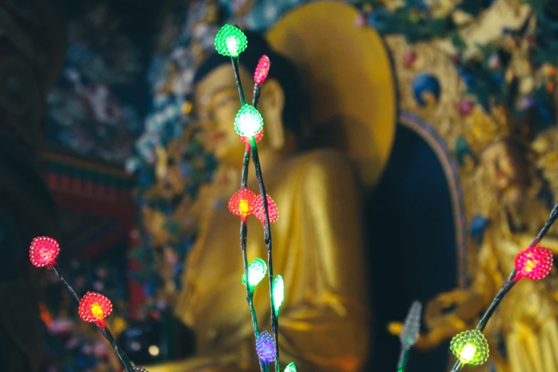 a lit up buddha figure sitting next to two little lights