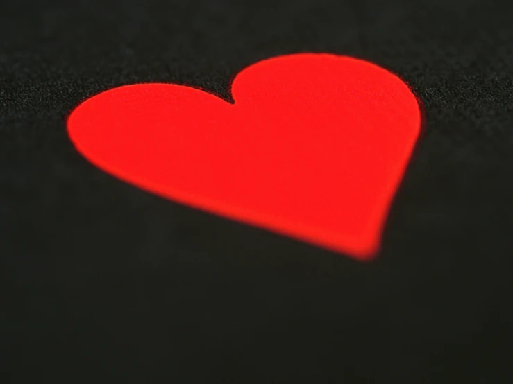 a red heart is shining across a black surface