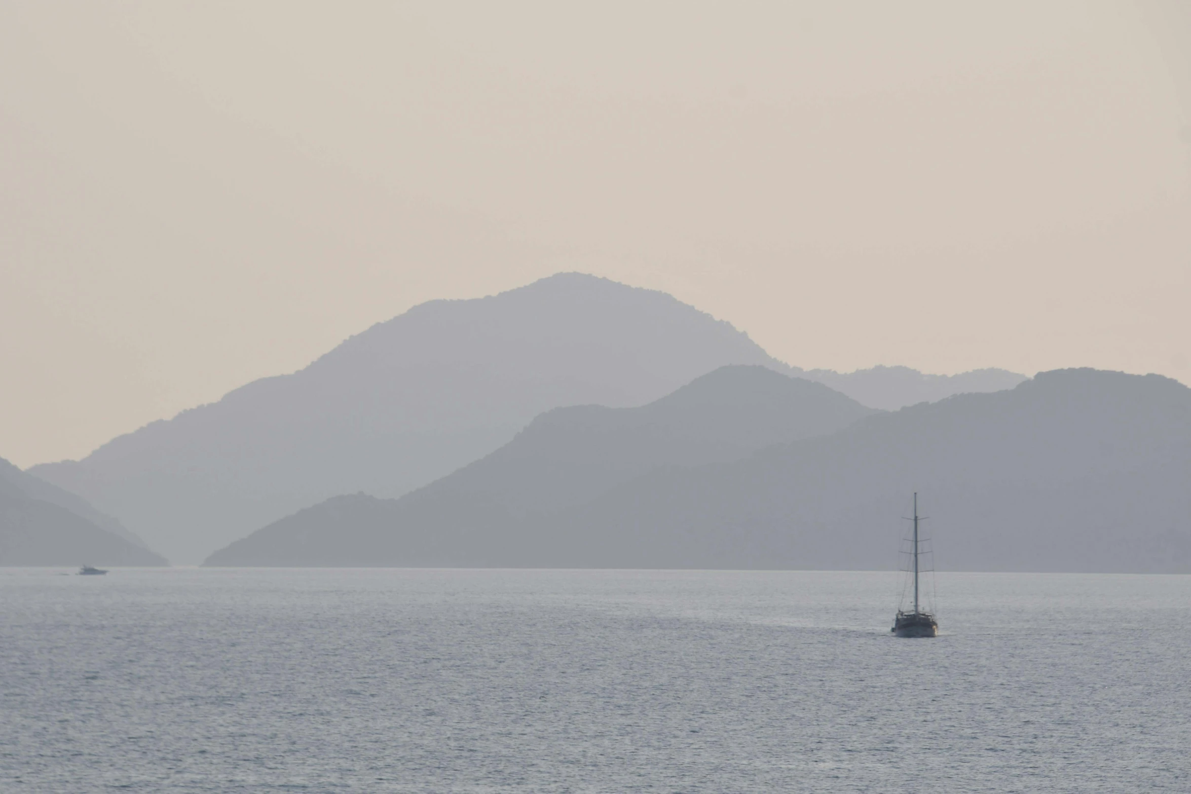 small boat with one mast out in the middle of a large body of water