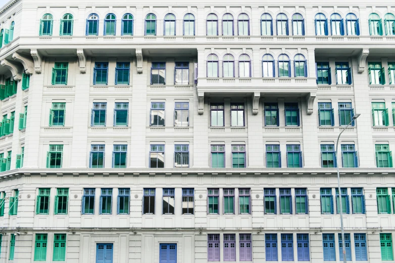 an unusual multi - story building has green and blue shutters