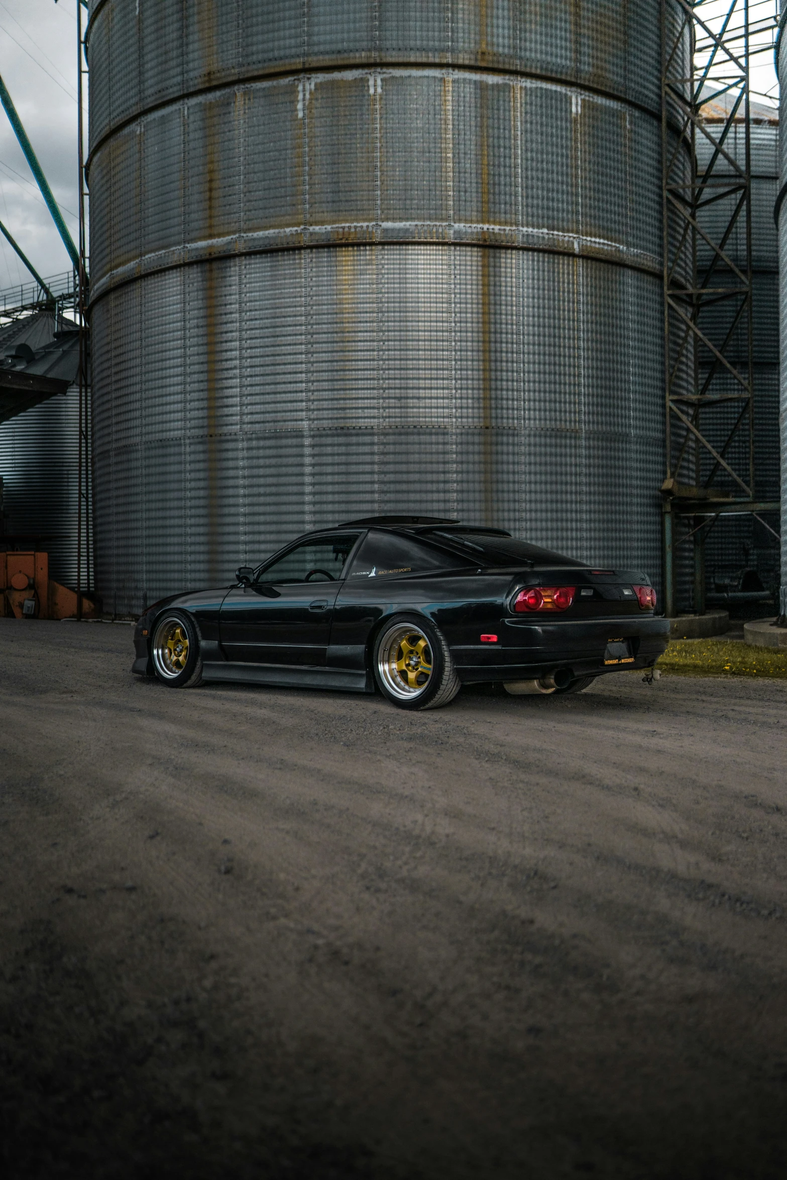 a sports car parked in front of an oil drum