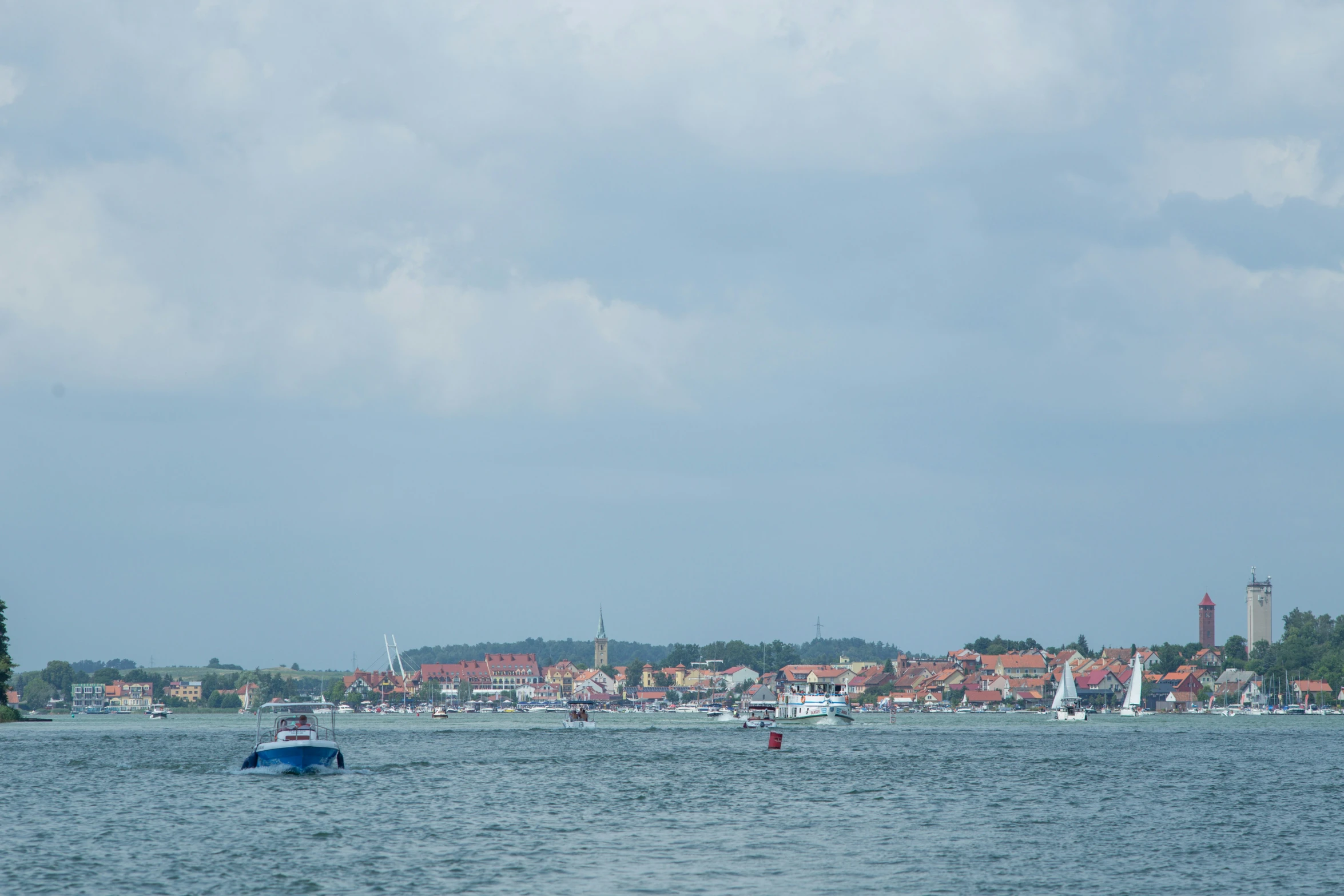 an area of ocean water with sailboats and buildings in the distance