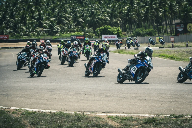 group of motorcycles on a race track with one rider getting into position