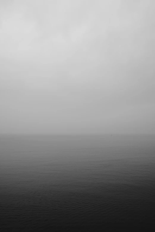 a large jet flying over the ocean on a cloudy day