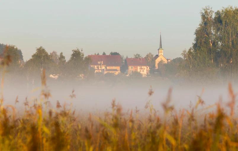 fog is in the air near houses with a bell tower on them