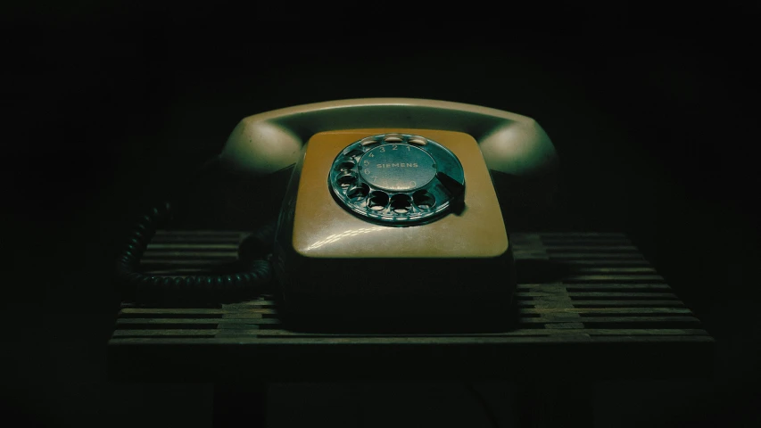 a rotary telephone sitting on the floor with its backlit by a light