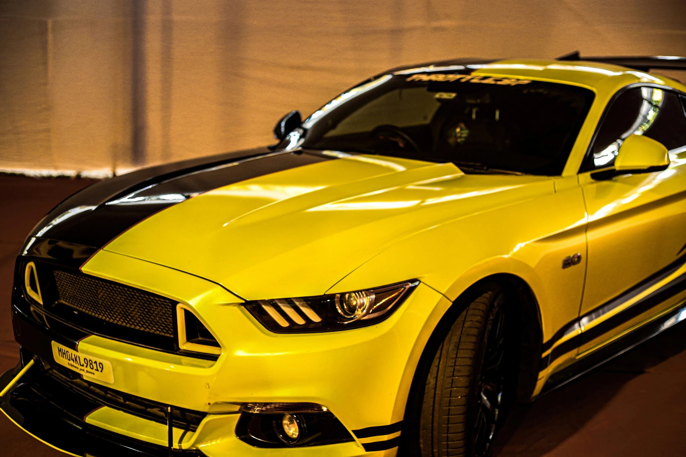 a yellow mustang car in the spotlight