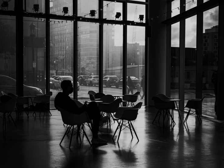 a woman sits outside near a window while she works on her laptop