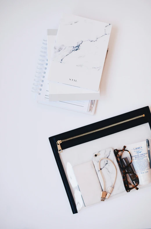 a glass case with a binder on it next to a notebook and pair of sunglasses