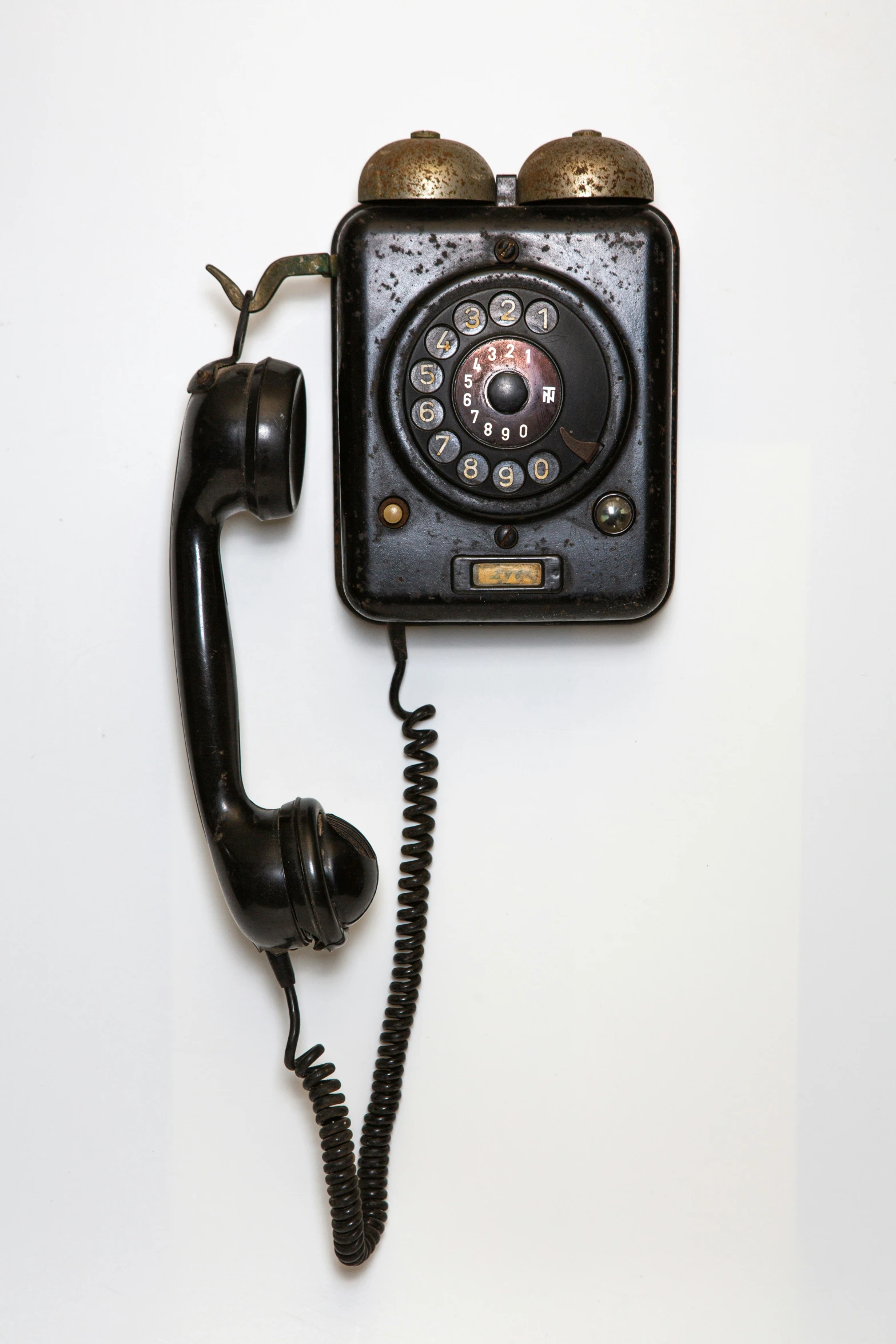 an old phone on the wall with two hands on it