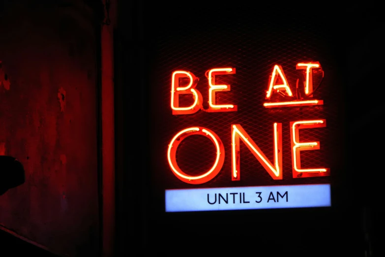 a red neon sign is shown with the words be at one on it