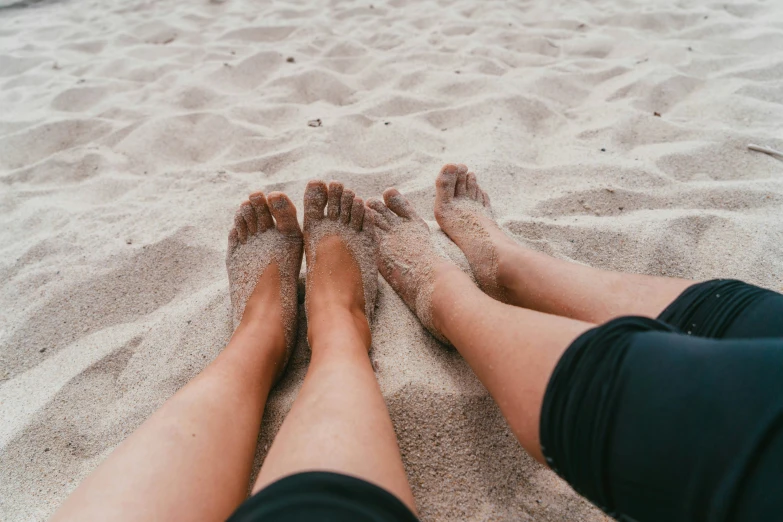 two people have their legs covered by sand