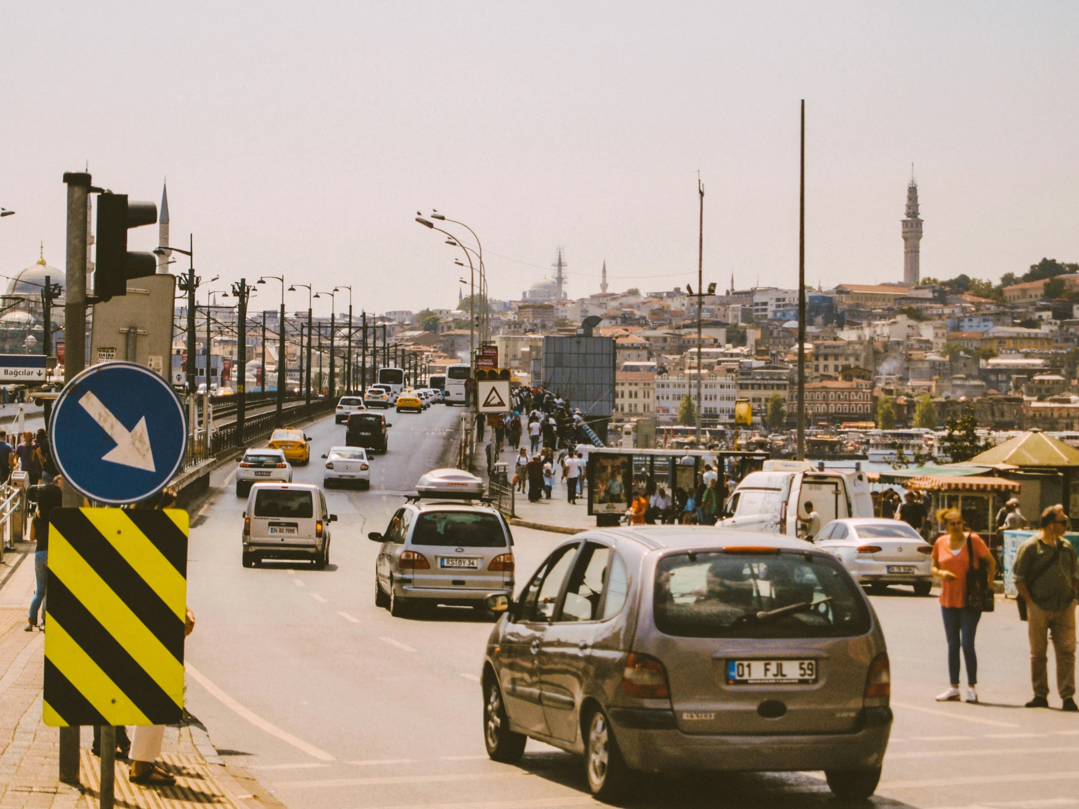 the city has a bunch of traffic as people are standing on a bridge