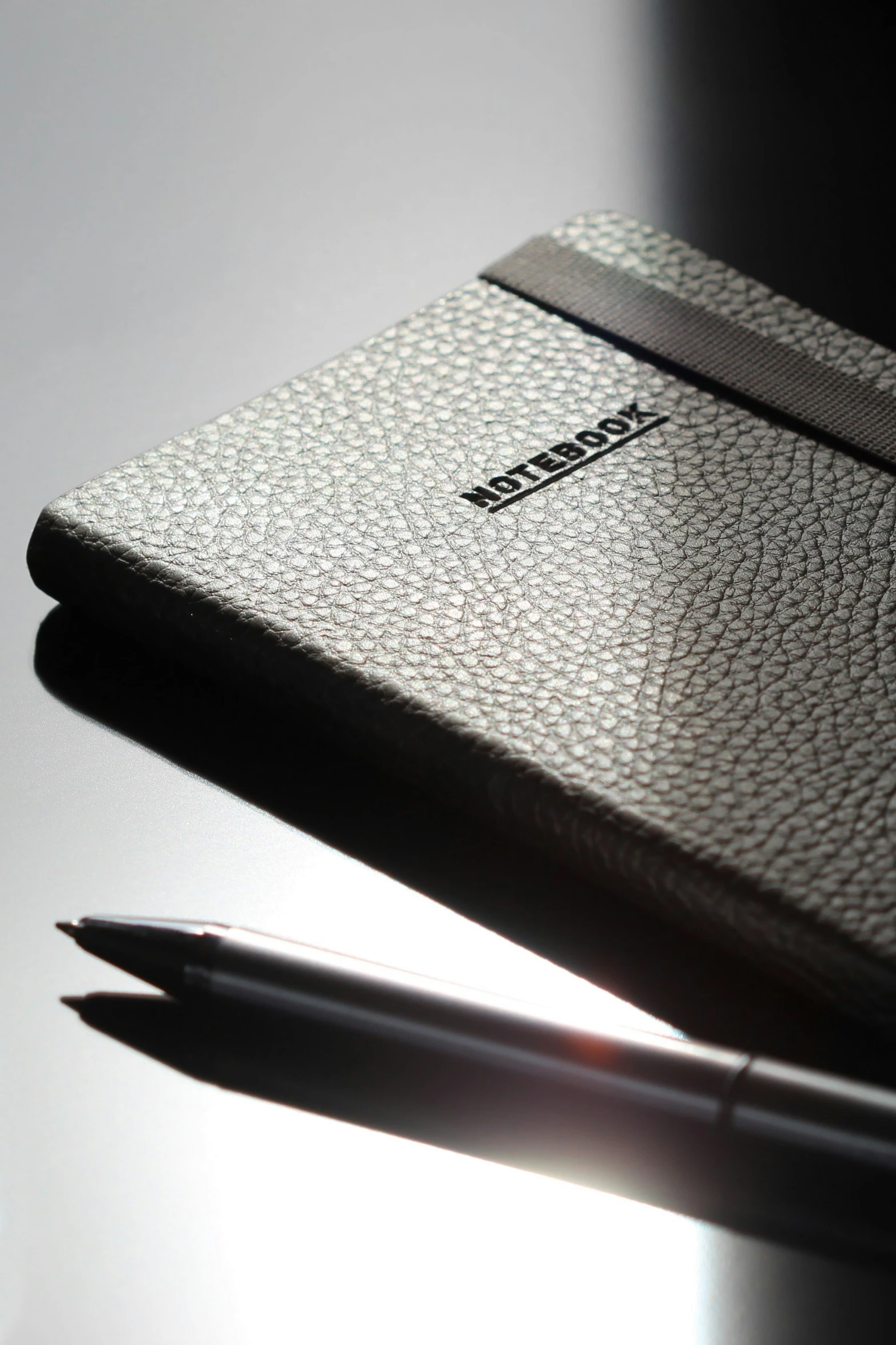 pen on white surface with black cover and business card holder