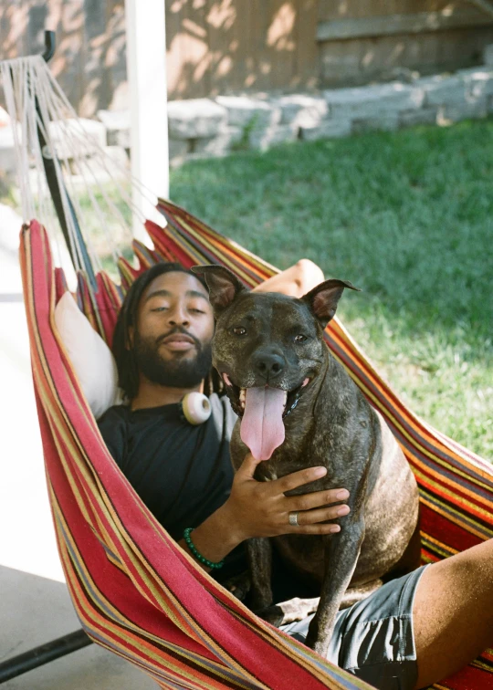 a man holding a dog in a hammock