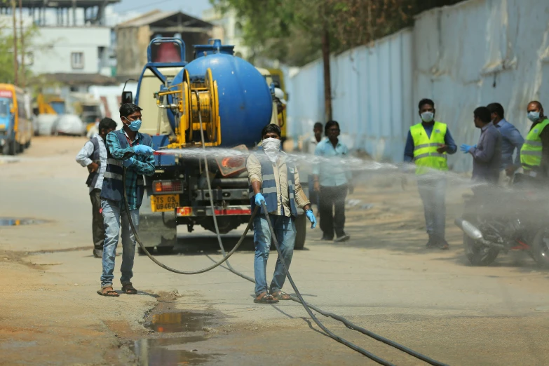 two people use a water hose to cool off on the street