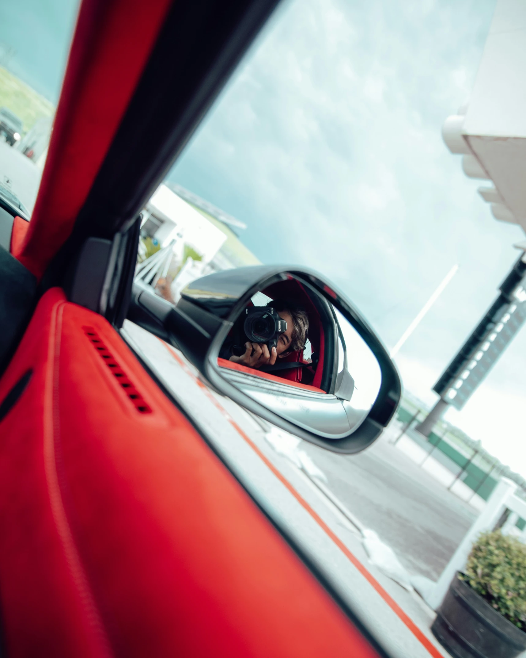 a person taking a picture in the mirror of a vehicle