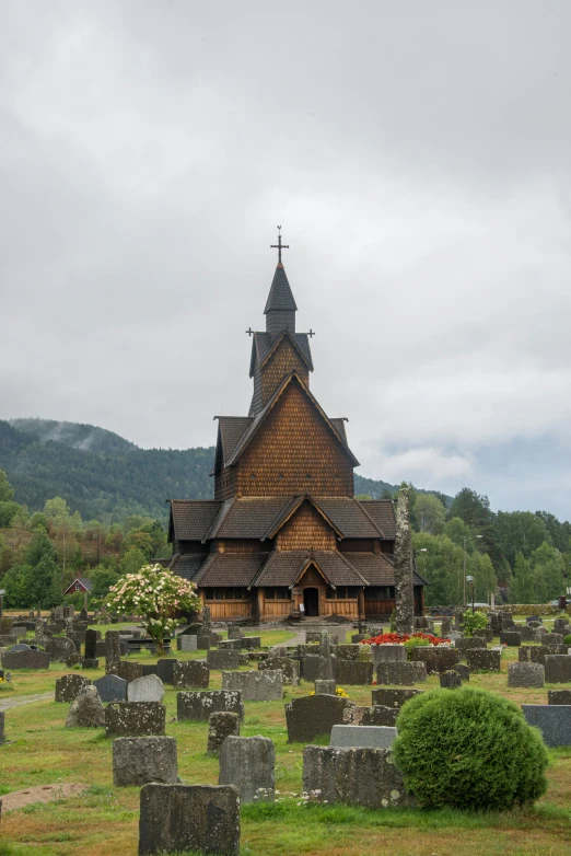 a large wooden church is surrounded by cemetery markers