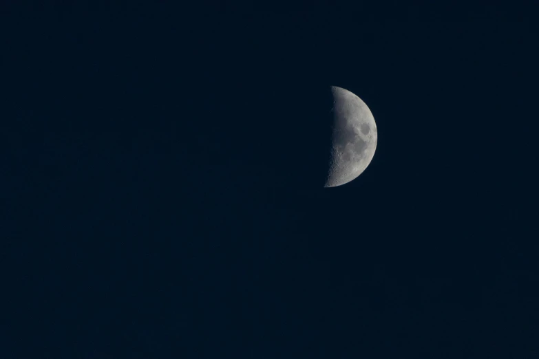 half moon seen through a dark cloud filled sky