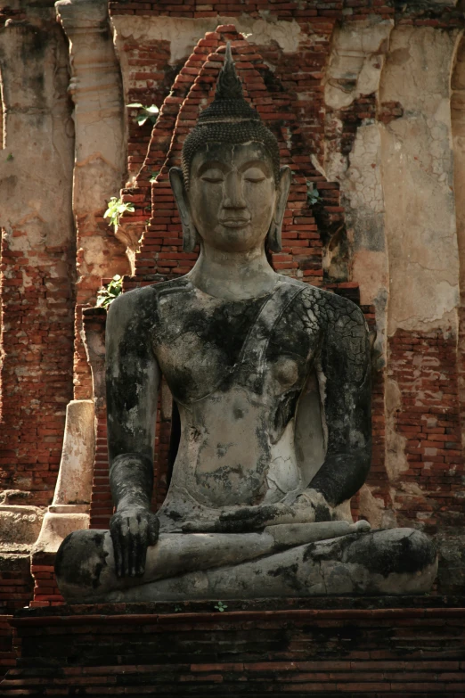 a statue of buddha sitting next to an old building