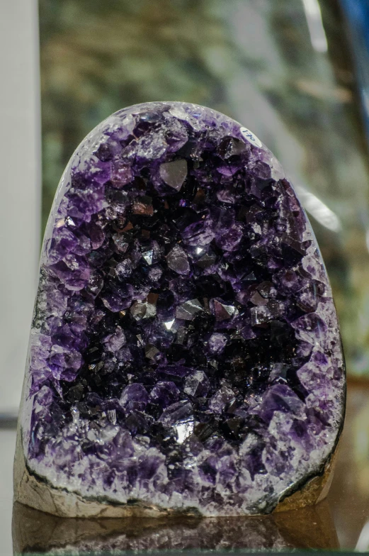 a large purple aystal on a rock with a glass vase behind it