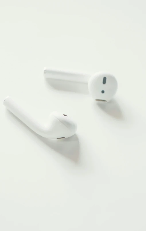 two white head phones on a white table