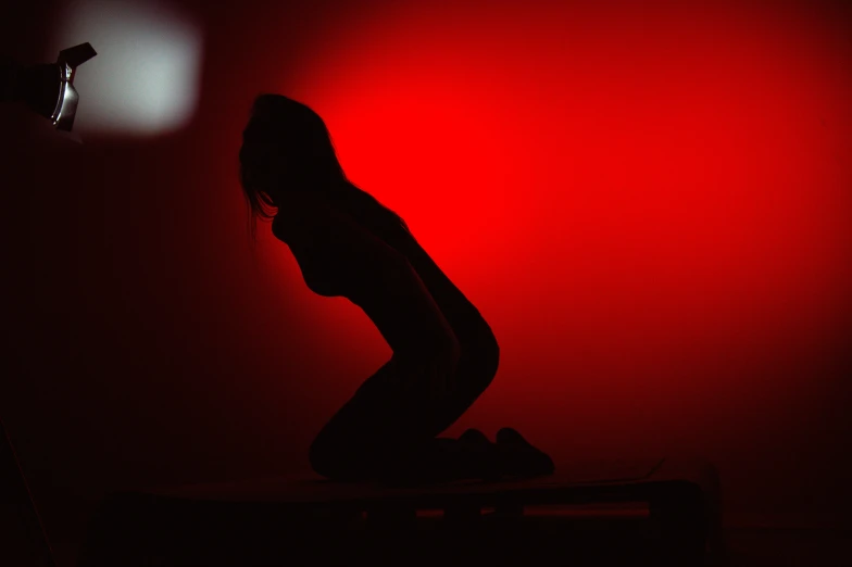a silhouetted woman standing in front of a red light
