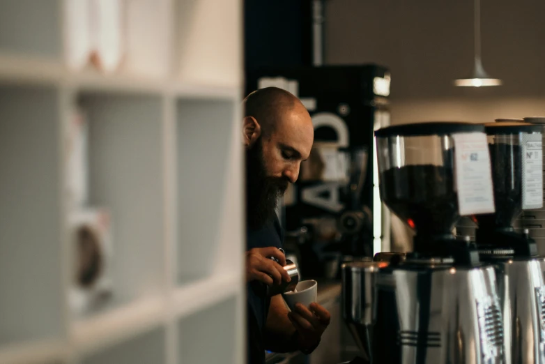 a man working in a coffee shop with coffee pots on the wall