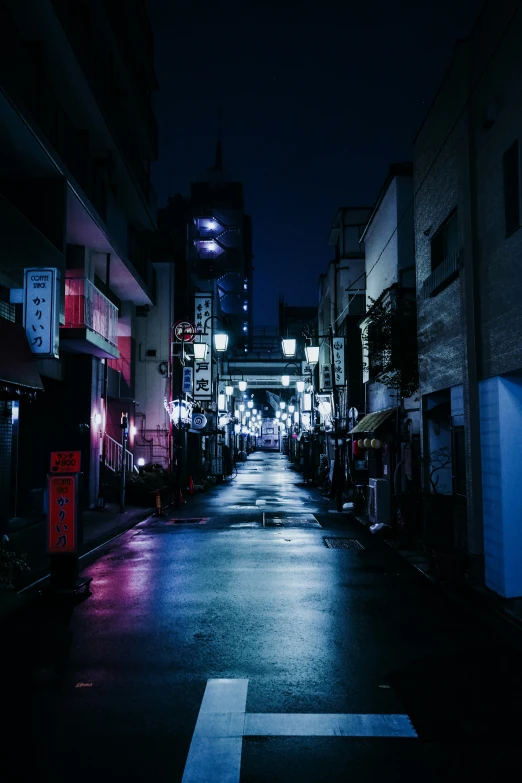 a dark street at night, with bright lights lit on buildings