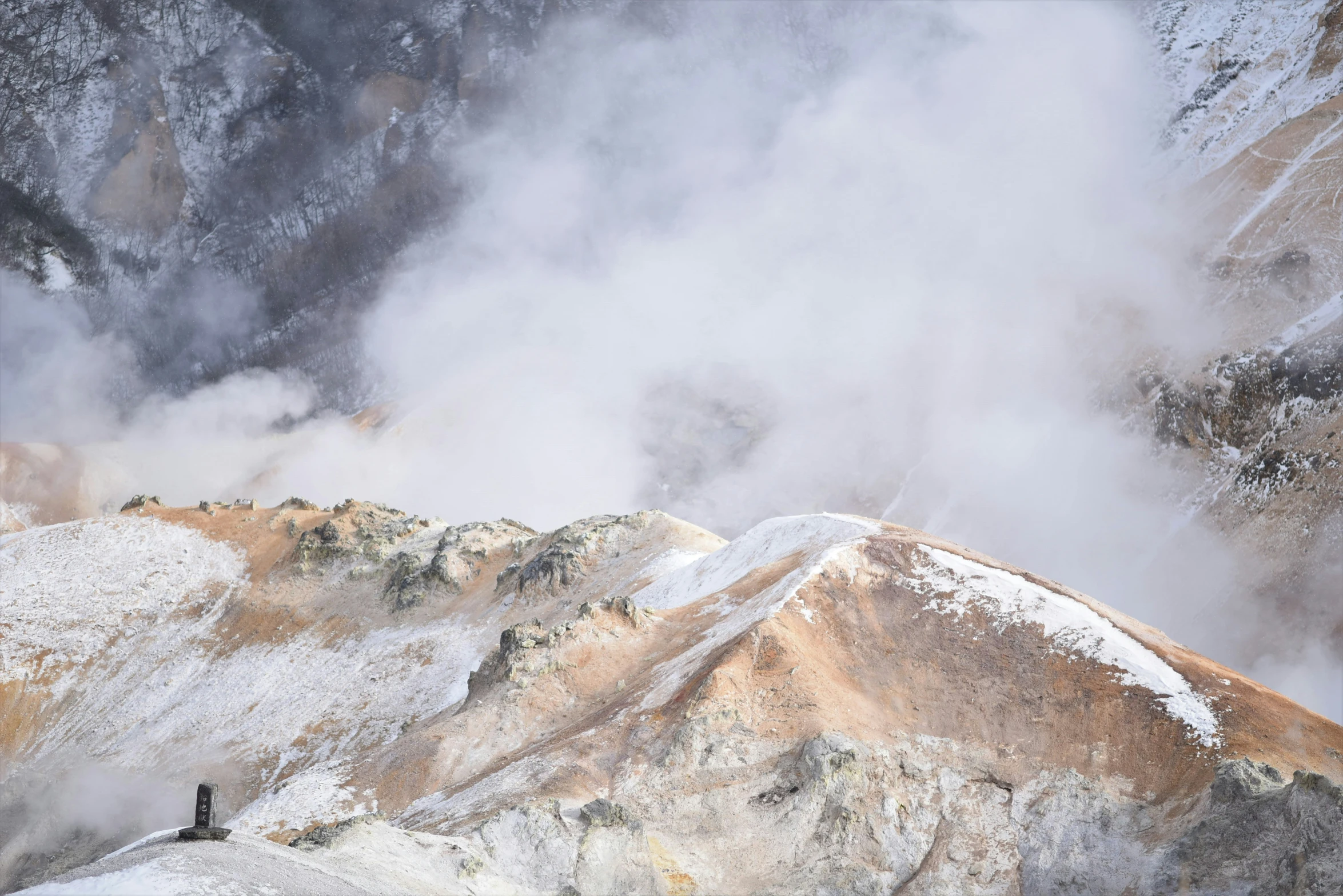 snow dusting mountains and clouds above a person walking