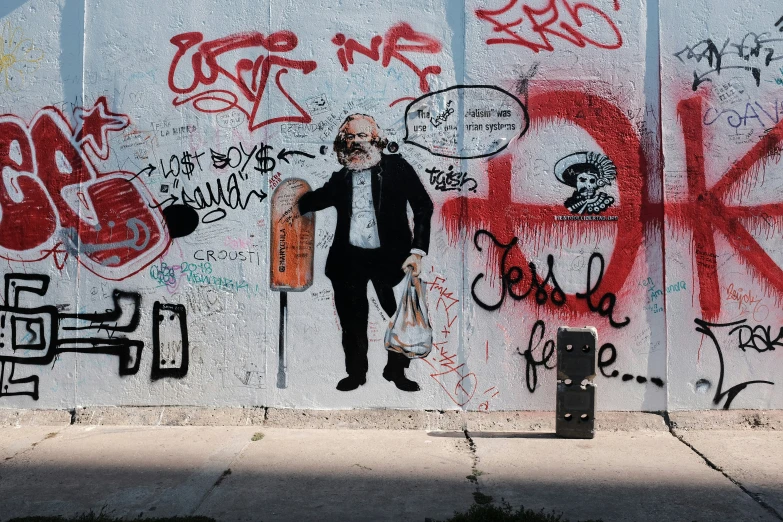 a man in a black suit is standing by a wall with some graffiti