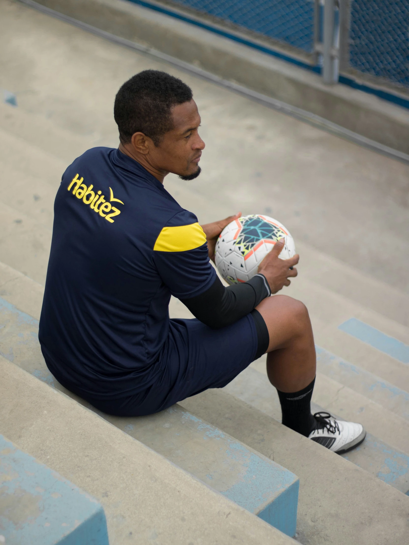 there is a male athlete sitting on stairs holding a ball