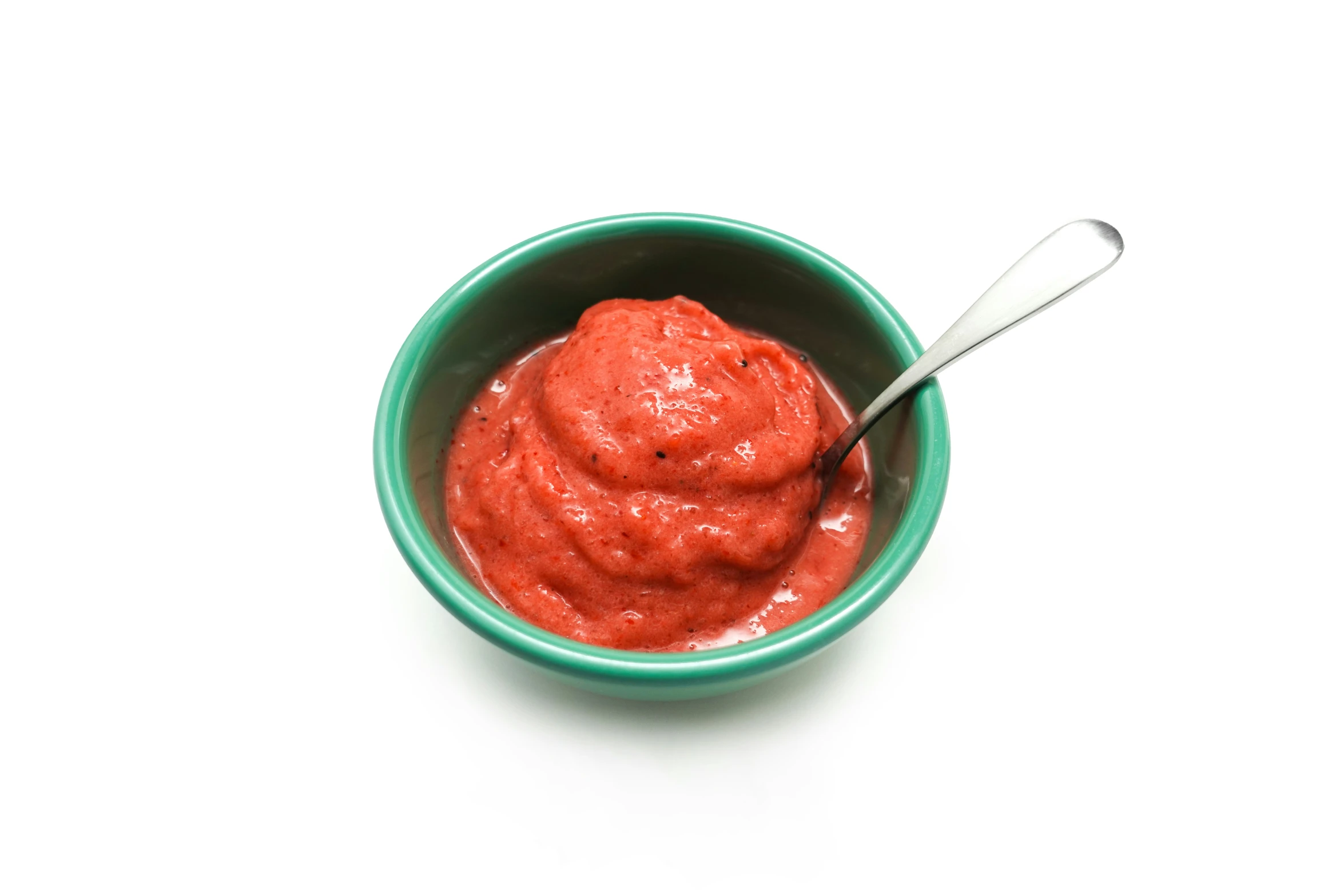 a bowl filled with red sauce next to a spoon