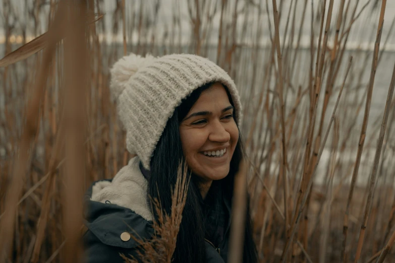 a woman with a white beanie smiles at the camera