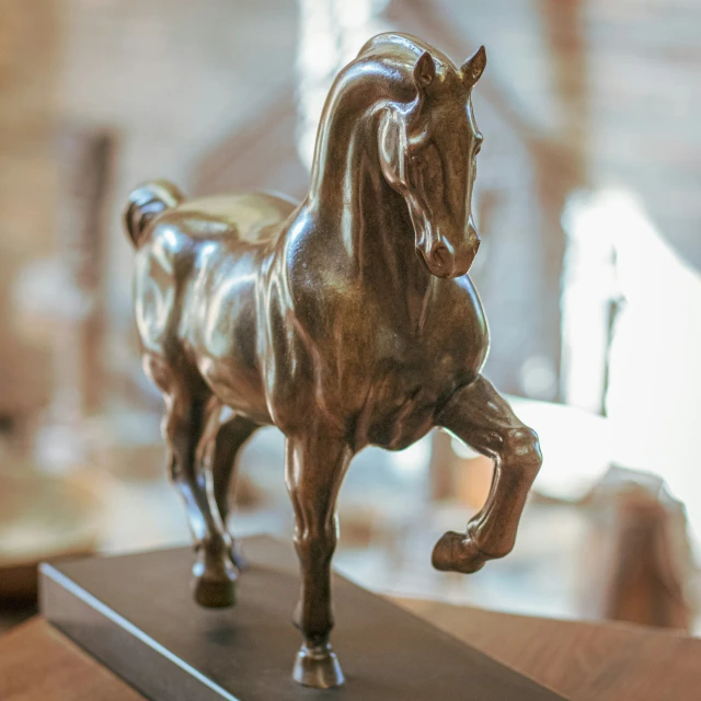 a bronze sculpture of a running horse on a table