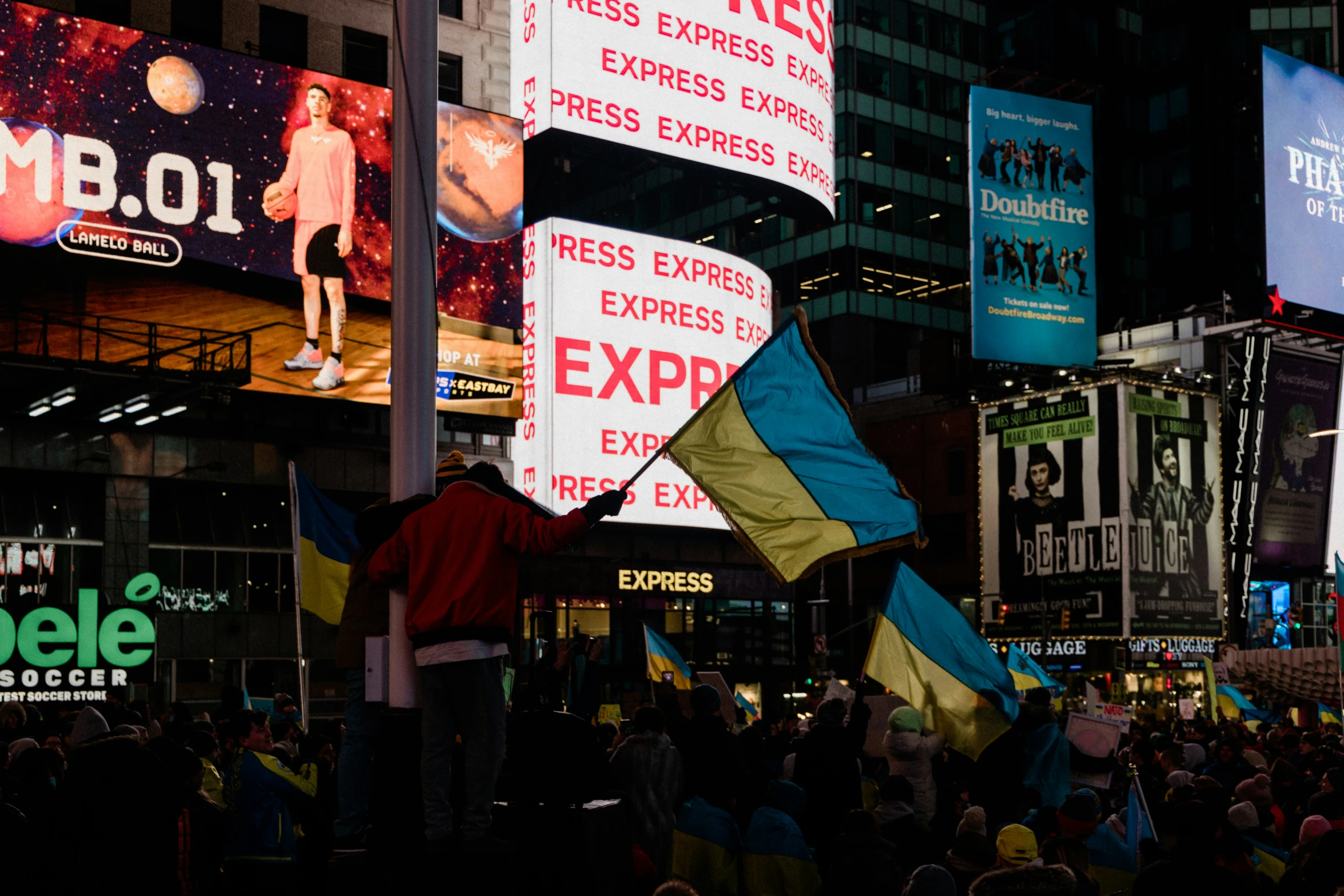 a crowd of people standing on a street with a bunch of banners